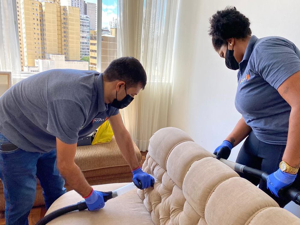 Dois técnicos da Inove Clean higienizando um sofá em apartamento
